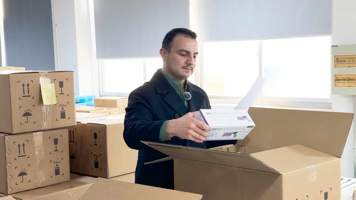 Denetçi, Çin'den sevkiyattan önce fabrika zemininde paketlenmiş kolileri kontrol ediyor